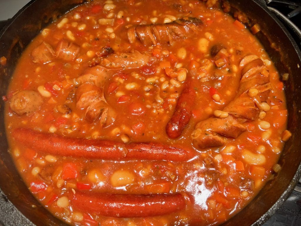 Deftiger Bohneneintopf mit Würsten aus dem Dutch Oven nach dem ... Deftiger Bohneneintopf mit Würsten aus dem Dutch Oven nach dem ...